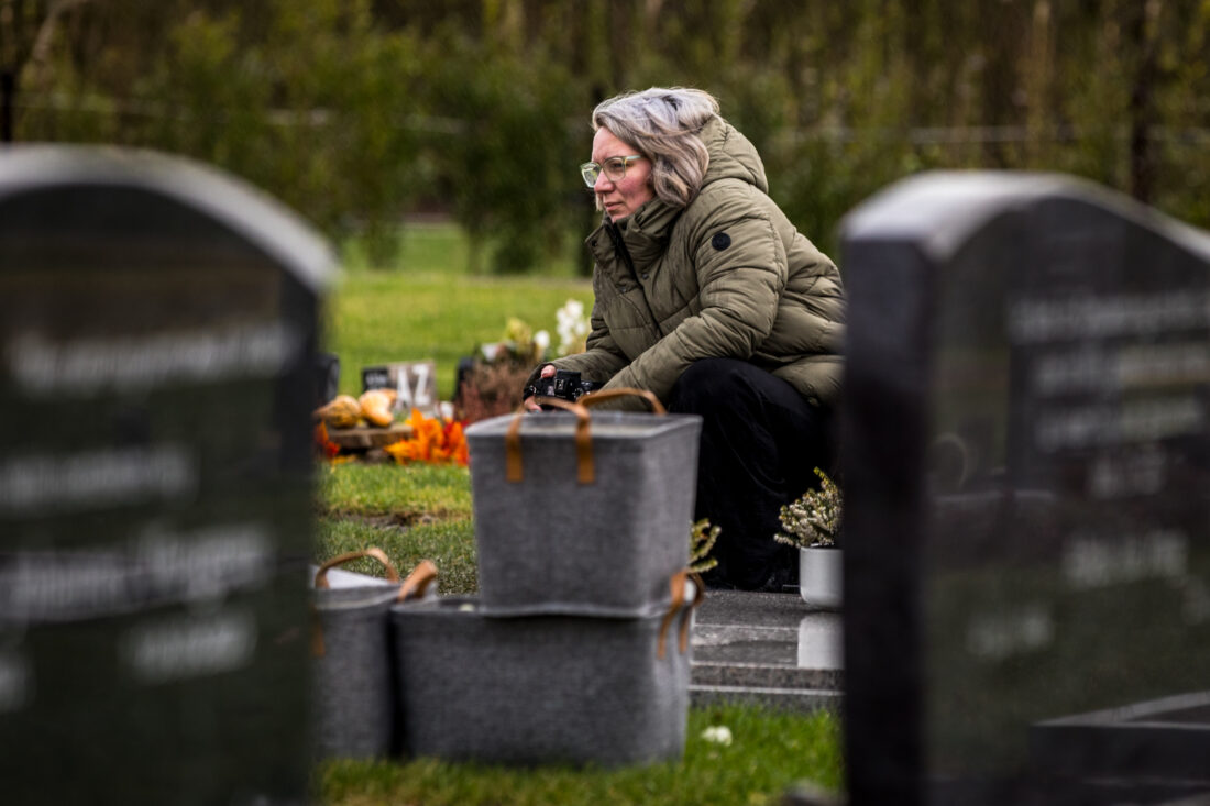 Afscheidsfotograaf gehurkt tussen de grafstenen tijdens een afscheid